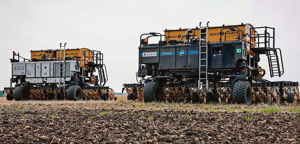 Two Raven robots in a tilled field.