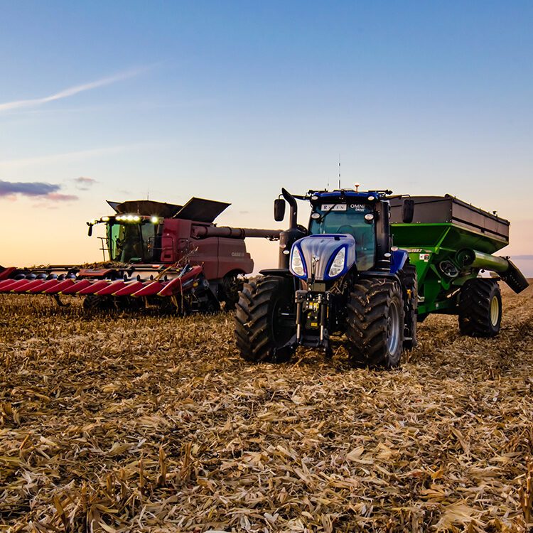 A tractor and a combine in a corn field.